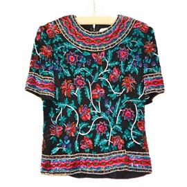 Niteline by Della Roufogali Vintage Beaded Top: A Niteline by Della Roufogali vintage beaded top. This short sleeve piece features an all over foliate and floral design in seed and tube beads with sequins on silk. The beads are in hues of red, blue and green with accents of gold beading on a black silk fabric. The piece is finished with a black polyester lining.