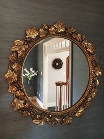 Round, gold gilt mirror with grape leaf motif border