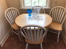 Drop leaf table with 4 chairs, displaying some collectible glass