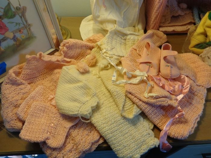 Crocheted baby sweaters with matching hats.