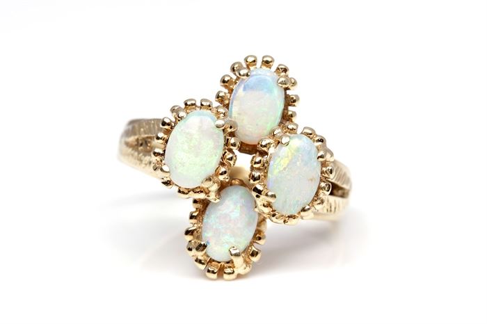14K Yellow Gold Opal Ring: A yellow gold diamond etched split shank holds four prong set oval cabochon white opal with prong like borders to each.