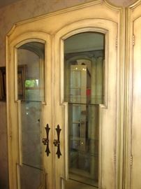 Two solid wood, china/curio cabinets, with a French Country feel.  Glass doors, sides and shelves, mirrored back, lighted, double door bottom storage area.  29-1/2" w, 15-1/2" d, 80" h.  Made in USA.