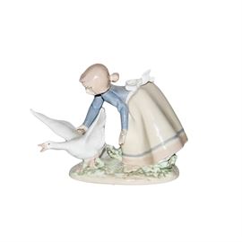 Lladro "Wild Goose Chase" Figurine: A Lladro hand-painted porcelain figurine titled Wild Goose Chase, model 5553. The figurine illustrates a girl leaning over to grab a goose. The goose is spreading its wings to try to escape. The piece is marked on the base with the maker’s mark and model number.