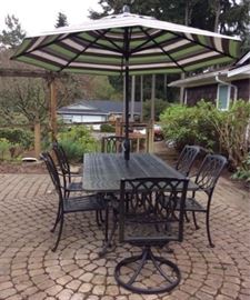 Black wrought iron style patio table, six chairs, Obravia umbrella and metal umbrella stand. Table measures 7ft long x 42in wide x 29in high. Two of the chairs have a swivel and tilt feature. All are in great shape and will shine with a gentle clean.