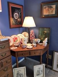 Early American style corner desk/table with 2 drawers.  Collectible rose plates, vintage china powder boxes.  Vintage fashion framed prints, "Dog Tired" by Barbara Shipman
