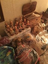 A small set of Humell statues sitting above a table full of dolls.