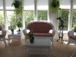 Wicker love seat, side chairs, and tables with spiffy coral upholstery.  Plants and wrought iron plant stands 