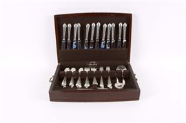 Alvin Sterling Silver "Romantique" Flatware: An Alvin sterling silver Romantique pattern flatware set. This sterling silver set features twelve knives with sterling hollow handles and stainless blades, twenty-four teaspoons, twelve dinner forks, twelve salad forks, one ladle, three serving spoons, one flat handle butter knife and one sugar spoon. Each utensil has an engraved “F” to the handle and is presented in a wooden “Pacific” silver cloth chest. The total approximate weight, excluding the knives with stainless blades, is 61.638 ozt.