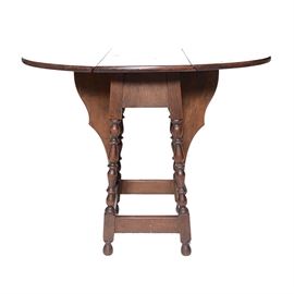 Antique Drop Leaf Table: An antique drop leaf table. This antique oval drop leaf side table has a walnut finish with four turned legs and square stretchers. The butterfly leafs fold out to support the drop leaf sides.