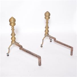 Vintage Brass Andirons: A pair of vintage brass andirons. These brass and iron pieces feature a spool form design on the front, with antler-shaped feet resting on round knobs.
