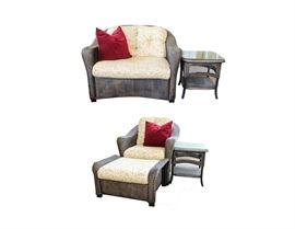 Lloyd Flanders Patio Set: A Lloyd Flanders patio set. This set includes a love seat, an armchair with an accompanied ottoman, and two side tables with glass surfaces. The frames are made of a dark brown wicker. The cushions are a beige and light yellow floral pattern. Each chair comes with red accent pillows.