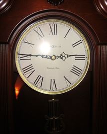 Howard Miller "Malia" quartz pendulum wall clock.  Solid wood, cherry finish, pediment top.  Westminster chime - #625466.  26-1/4" tall, 12-1/4" wide, 5-1/2" deep.
