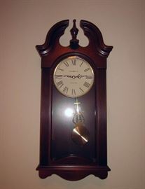 Howard Miller "Malia" quartz pendulum wall clock.  Solid wood, cherry finish, pediment top.  Westminster chime - #625466.  26-1/4" tall, 12-1/4" wide, 5-1/2" deep.