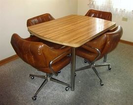 Mid Century dinette set: Woodgrain Formica top table with tubular chrome legs, four faux leather swivel arm chairs on casters.