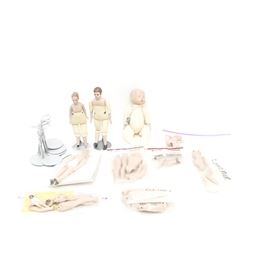 Collection of Small Doll Parts and Stands: A collection of small doll parts and stands. The collection includes a male and female doll body, a baby doll body and miscellaneous limbs for smaller dolls. Also included are a set of doll stands.