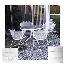 White Metal Patio Set and Plant Stands: A white metal patio set and plant stands. Included are a round white coated metal dining table and four matching white coated metal chairs. The table top is made of textured clear glass and there are six green retro floral patterned vinyl seat cushions that fit the chairs. Also included are two white coated metal plant stands with multi-tiered plant shelves. No maker’s marks.