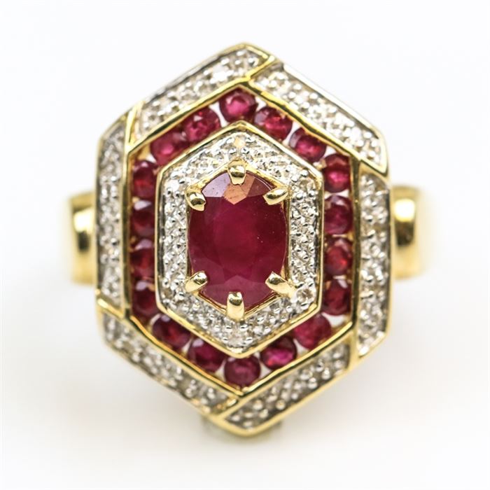 14K Yellow Gold, Ruby, and Diamond Hexagonal Cocktail Ring: A 14K yellow gold hexagonal cocktail ring featuring one center oval cut ruby framed by alternating layers of diamonds and smaller channel set rubies.