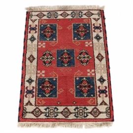 Handwoven Anatolian Accent Rug: A handwoven Anatolian accent rug. The piece features a central medallion with matching spandrels to each corner in a palette of deep blue, red, taupe, and black that sits on top of a deep red field. The field is populated by several medallions to the center in a complementary palette and it is surrounded by a compound resolved border. The border features a pattern of abstract elements in deep blue, red, and cream with a wool fringe to either end. The piece is not marked.