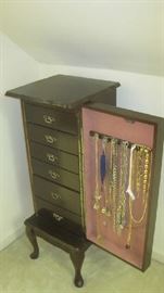 Open armoire with jewelry drawers and hooks on door with costume jewelry 