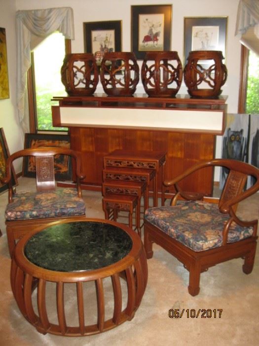 Four marble top Asian stools atop a mid century bar. Two opium chairs flank set of three nesting tables. Green stone round coffee table.