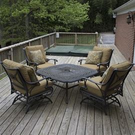 Outdoor Coffee/Firepit Table and Rocking Armchairs: An outdoor coffee/firepit table and rocking armchairs. The center of the square cast metal coffee table can be lifted out and replaced with the firepit bowl insert and mesh cover. The Agio rocking armchairs feature cast metal frames and brown woven vinyl seats. Back and seat cushions with throw pillows for each chair are included.