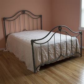 Queen Size Wrought Metal Bed Frame: A queen size wrought metal bed frame. The metal headboard and footboard each feature a humped double-rail with spindle supports, a wreath accent in the center between the two rails, and floral embellished elbow fittings connecting the upper rail with the cylindrical legs. An attached metal frame supports the mattress. Please note mattress is not included. This item will require tools to disassemble.