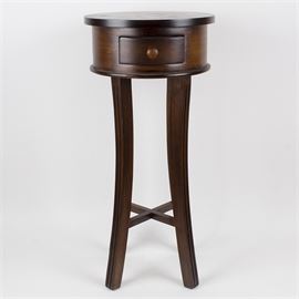Dark Wood Round Accent Table: A dark stained wood accent table. The table comprises a round overhanging top, a small single drawer in the apron, and saber legs with an “X” brace. A label inside reads “KV Made in Thailand”.