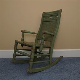 Antique Child's Rush Seat Rocking Chair: An antique child’s rush seat rocking chair. This Eastlake-style green rocking chair features solid wood construction with a cane seat and back. The chair back is topped with a pierced panel, fluted sides, and turned arms.