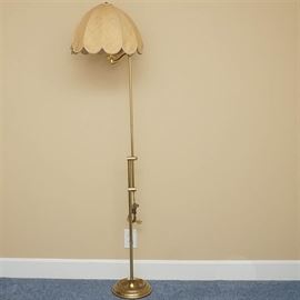 Adjustable Floor Lamp Including Scalloped Shade: An adjustable floor lamp. This selection showcases a brass tone, adjustable frame. Also included a woven, beige domed and scalloped shade. There are no visible brand markings.