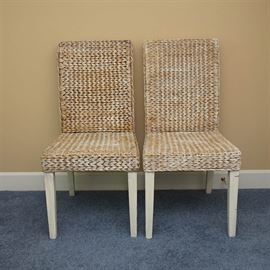 Woven Parsons Style Chairs: A pair of Parsons style chairs. These chairs feature straight backs and seats composed of a woven material with a distressed white wash finish. Each rests on four tapered legs with a white painted finish.