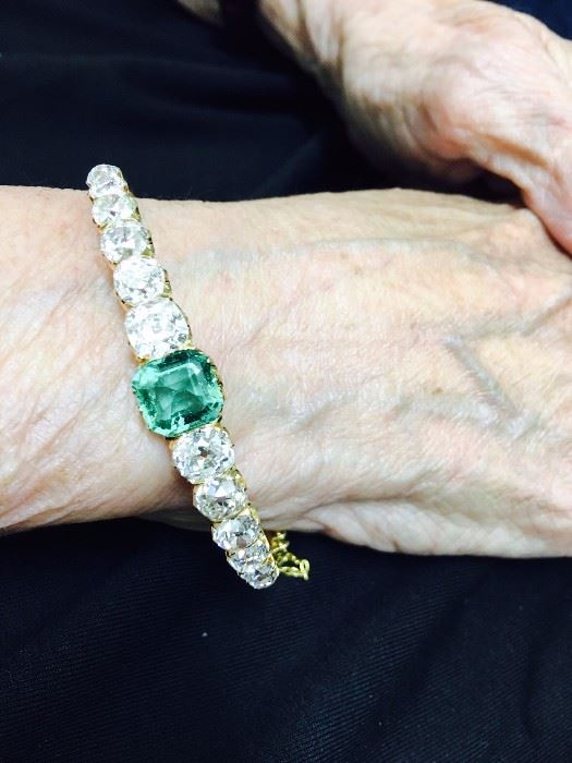Antique diamond and emerald bracelet.  Set with twelve old mine cut diamonds weighing approx 6 carats total.  Set in the center is a natural emerald of approx 2.25 carats.  Unmarked yellow gold.
