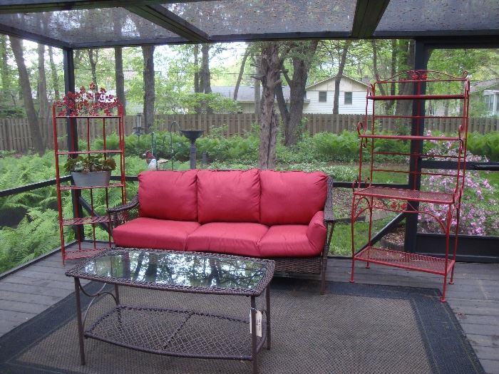 Outdoor wicker furniture, sofa w/extra set of cushions, red metal racks. coffee table, floor rugs