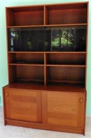 Located in 92103 zip area. Mid-century, Danish modern teak bookcase/cabinet made by Domino. 6ft high, 4ft wide, 11.5" deep at top, 19.5" deep at bottom. Smoke colored sliding glass doors. $275.