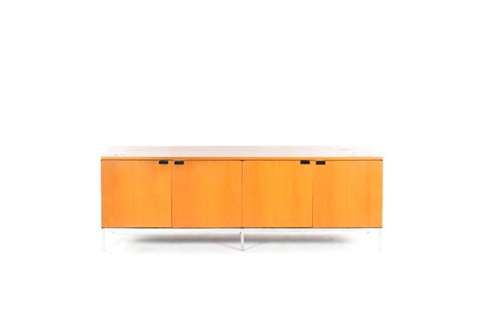 Mid Century Modern Florence Knoll Four Position Credenza: A Mid Century Modern four position credenza designed by Florence Knoll. This piece has a golden oak stained finish and a single row of blind cabinet doors with magnetic closures behind the recessed metal handles. It stands on four straight metal legs.