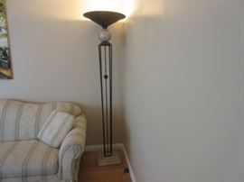 Elegant floor lamp with rod iron and marble base and globe holding up the top metal shade.