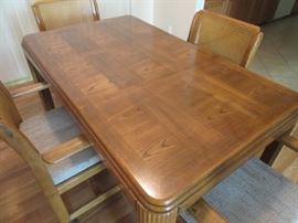 Beautiful solid oak dining / kitchen table with four chairs on wheels. Chairs are also oak with cushioned seats and woven insets on the back. Middle leaf can be removed for a smaller area.