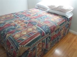Double size bed; frame on wheels, box spring and mattress with pillows and comforter shown.