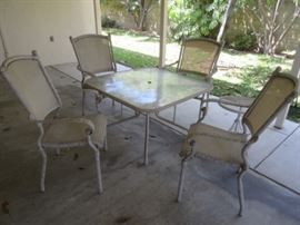 Outdoor patio set with heavy rod iron framing in the chairs and table; table is topped with a glass piece, and there is a hole in the middle for an umbrella (there is no umbrella included); plus a small round side table.