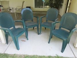 Set of four heavy-duty green plastic outdoor chairs.