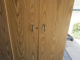 Set of three cupboards with two doors and multiple shelves inside, doors have a keyed lock on the outside. One of the units is damaged, the front door has come off on the right hand side.