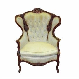 Antique Carved Wooden Chair: An antique carved wood chair. The chair has a wooden frame with decorative carvings. It is covered in a cream colored fabric. This chair has a higher back and winged sides. It is unmarked. It matches sofa item 122 and is similar to chair item 121 in this sale.