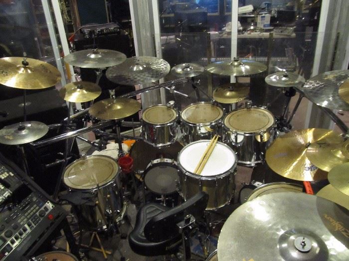 A most extensive drum kit made up of: 
4x toms: 10" (8" depth), 12" (9" depth), 13" (10" depth), & 14" (14" depth) floor Tom. 
2x base drums: 22" (18" depth) 
14" (11" depth) snare 
3x Zildjian ZXT 10" titanium splash cymbals 
10" Zildjian brass splash 
10" Zildian brass rock splash 
2x sets of 14" brass, A custom projection hi-hats 
Zildjian ZXT set of 14" brass hi-hats 
10" Zildjian EFX No. 1 
9" LP hi-bell 
16" Zildjian ZXT brass medium thin crash 
2x 16" Zildjian ZXT titanium rock crash 
2x 20" Zildjian ZXT titanium rock rides 
16" Zildjian platinum medium crash 
20" Paiste brass power ride 
20" Zildjian ZXT medium ride 
18" China Paiste ride 
22" Zildjian ride 
Gibraltar round rack system/cage, as well as hardware for Gibraltar. 
Pearl arms 
DW 5000 chain drive double base drum pedals 
Ludwig drum throne, high back 
8x Roland triggers 
15x cymbal stands and arms 
Pearl hi-hat stand 
LP cow bell 
bunch of drum heads 
snake 
Alexis DM Pro and DM 5 drum modules 
16 channel Mackie CR1