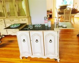 The front of the bar cart opened. Inside the Cabinet are glass holders with glasses. 