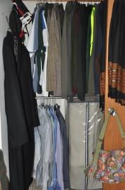 Walk in closet with men and woman's clothing as well as linen and other bedding.