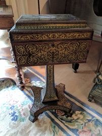 English Regency period coffer-form tea caddy on stand (or teapoy), hinged top above four canisters with brass scrollwork decorated (or Boulle-work) lids, quatrefoil base with casters.
