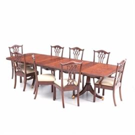 Eight Maitland-Smith Chippendale Style Chairs with Table: A fine mahogany dining table and eight chairs, by Maitland-Smith. The extension table has a rectangular top with figured veneer and two matching leaves, all with reeded edge, over twin, turned pedestal bases, supported on three splayed legs with brass feet and casters. The chairs include two arm and six side chairs, each having foliate and pierced carved backs in the Chippendale style, over slip-seats, upholstered in an ivory raw silk, appearing fabric. Custom pads included.
