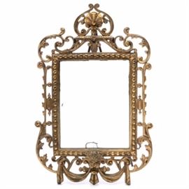 Victorian Style Cast Metal Easel Back Frame with Mirror: A Victorian style cast metal easel back frame with mirror. The gold-tone frame features ornate scrolled acanthus leaves with a shell motif crest and a draped lion’s head to the base. The back is supported by a swing easel stand. Unmarked.