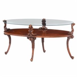 Carved Mahogany Glass Top Coffee Table: A carved mahogany glass top coffee table. This table has an oval glass top resting on carved acanthus brackets. It rests on cabriole legs with carved leaf knees and scrolled feet. It matches a side table with item number 17CIN224-454.
