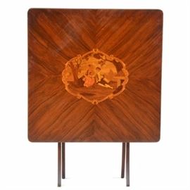 Vintage Inlaid Walnut Folding Table: A circa early to mid-20th-century vintage folding table, in walnut. It has a finely inlaid design to the center of the tabletop, depicting a man and woman in aristocratic attire. The tabletop has book matched wood grain, and rounded corners. It stands on a folding base with curved legs and a lathe-turned spreader. The piece is marked to the underside: the maker’s name is illegible, but there is a date mark which appears to read 1934.