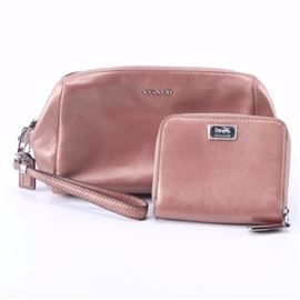 Coach Wristlet and Wallet: A Coach wristlet and wallet. This selection includes a wallet and a wristlet that showcase metallic rose gold tone leather. They are each labeled by the manufacturer.